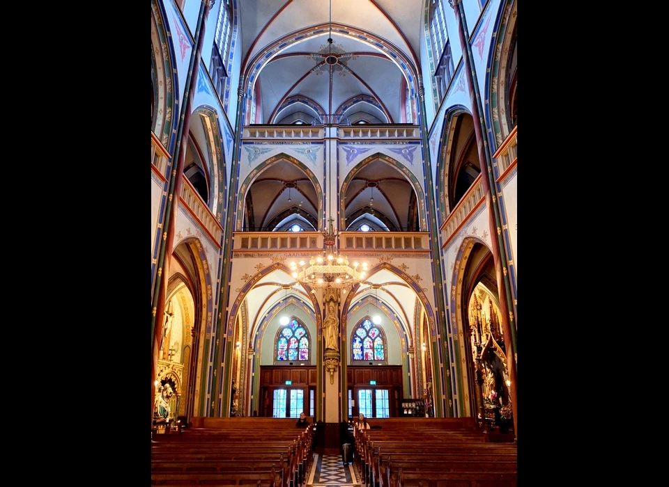 Singel 442-446 de Krijtberg interieur naar entree. De twee glas-in-loodramen boven de ingang zijn van Gisèle d'Ailly-van Waterschoot van der Gracht. Het linker personifieert de Vrede tussen de Wijsheid en Rechtvaardigheid en dateert uit 1945; het rechteris uit 1946 en personifieert de drie goddelijke deugden, geloof, hoop en liefde (2025)